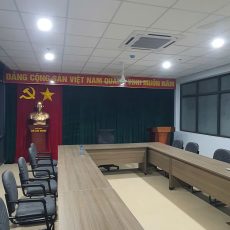 Phông hội trường với rèm cuốn cửa sổ hai bên sân khấu và bàn chủ tọa